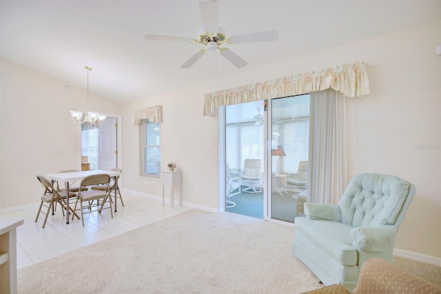 interior space featuring ceiling fan with notable chandelier, a wealth of natural light, lofted ceiling, and light tile patterned flooring