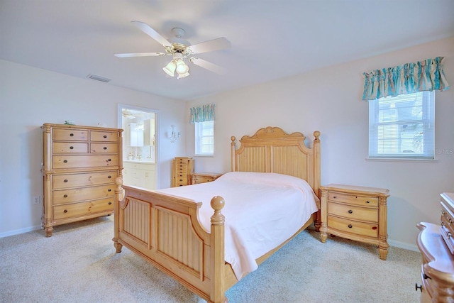 carpeted bedroom featuring ceiling fan, multiple windows, and ensuite bath