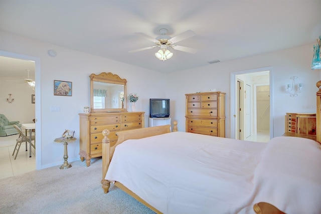 bedroom with connected bathroom, light colored carpet, and ceiling fan