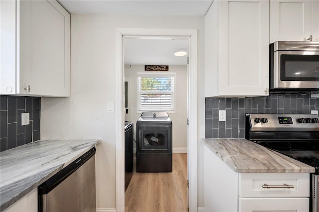 kitchen with decorative backsplash, appliances with stainless steel finishes, separate washer and dryer, light hardwood / wood-style flooring, and white cabinetry