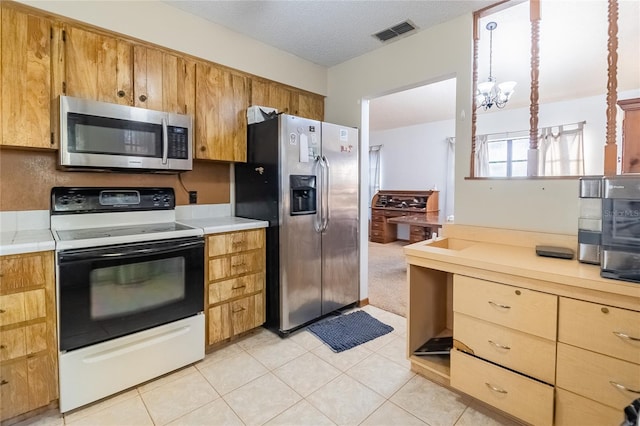 kitchen featuring light tile patterned floors, stainless steel appliances, a textured ceiling, and a notable chandelier