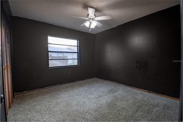 carpeted empty room featuring ceiling fan and a textured ceiling