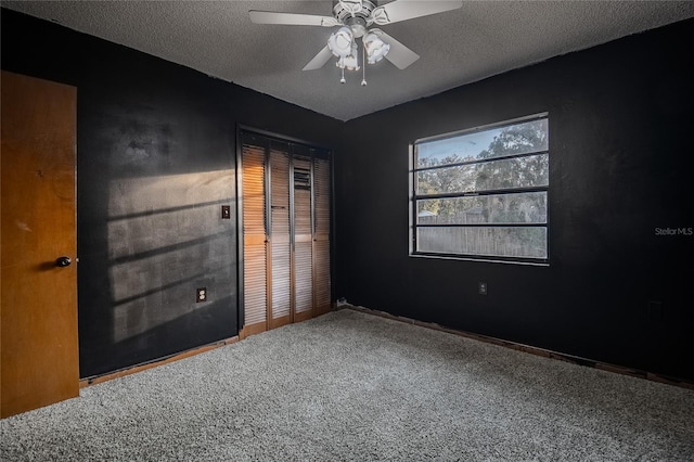 unfurnished bedroom with carpet flooring, a textured ceiling, a closet, and ceiling fan