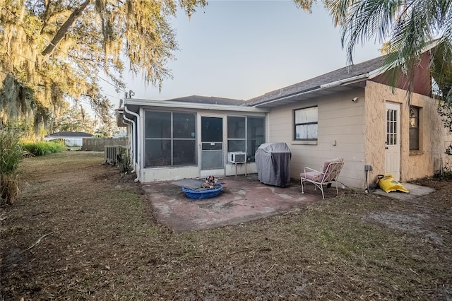 back of property with a lawn, a patio area, and a sunroom