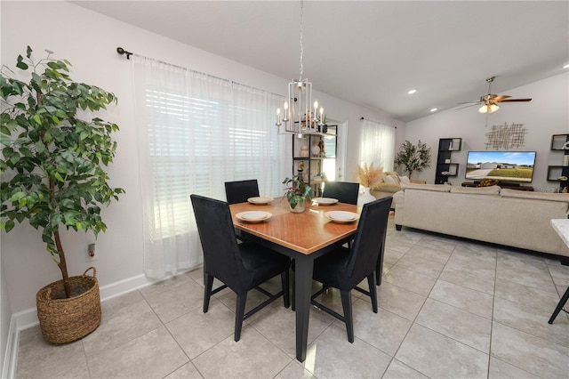 dining room featuring ceiling fan with notable chandelier, light tile patterned flooring, and vaulted ceiling