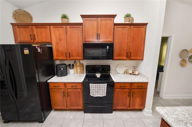 kitchen featuring light stone countertops, light tile patterned floors, and black appliances