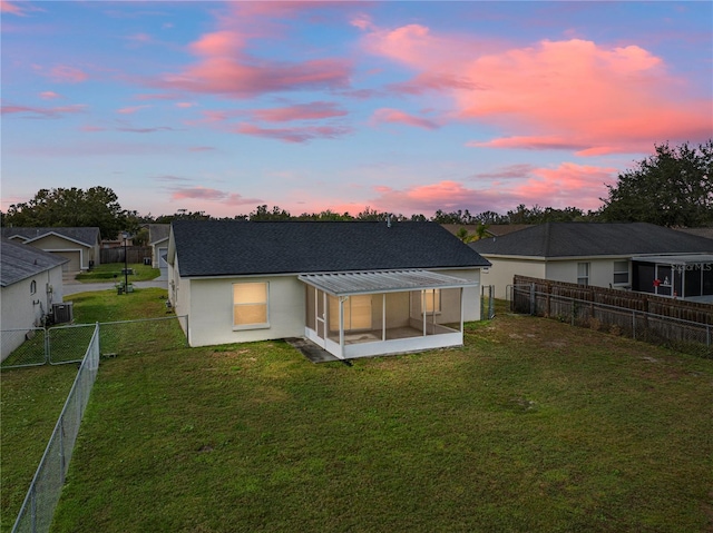 back house at dusk with cooling unit and a lawn