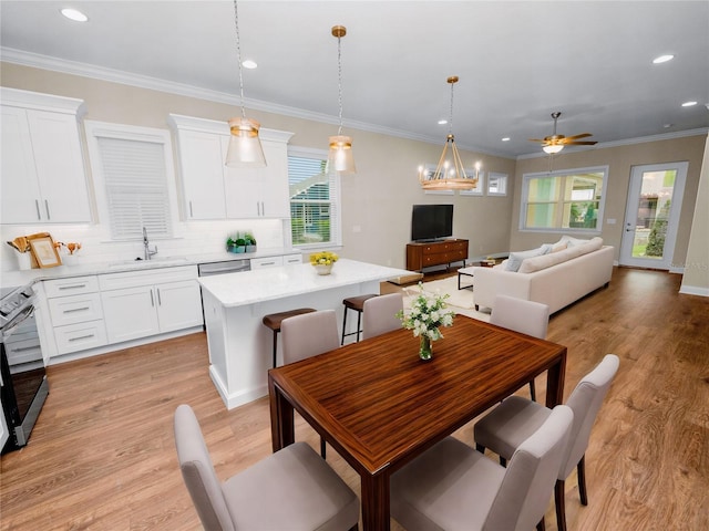 kitchen featuring a kitchen island, pendant lighting, ceiling fan with notable chandelier, white cabinets, and sink