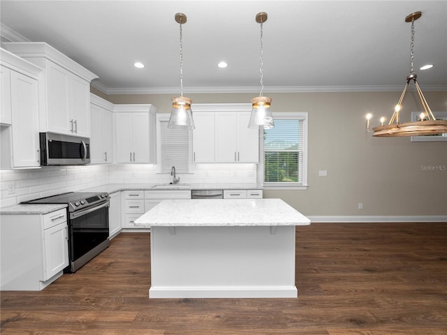 kitchen featuring appliances with stainless steel finishes, a kitchen island, white cabinetry, dark hardwood / wood-style flooring, and hanging light fixtures