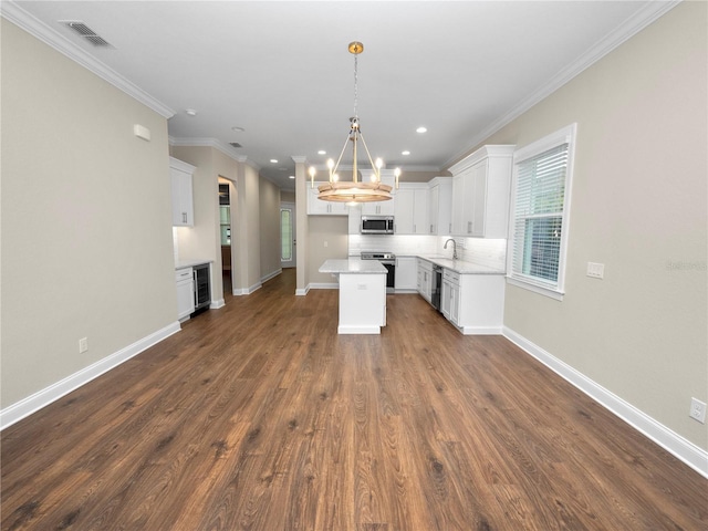 kitchen with decorative light fixtures, a center island, white cabinetry, appliances with stainless steel finishes, and dark wood-type flooring