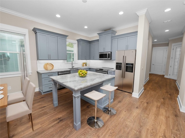 kitchen featuring appliances with stainless steel finishes, a kitchen island, a kitchen bar, decorative backsplash, and light stone counters