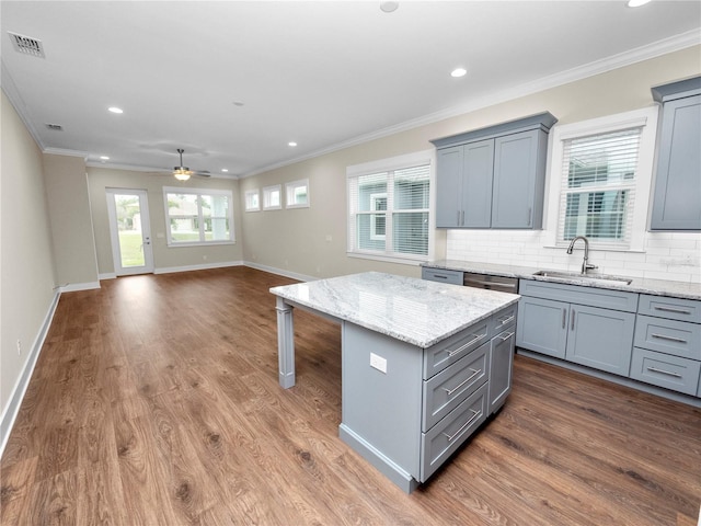 kitchen with ceiling fan, a wealth of natural light, backsplash, a kitchen island, and sink