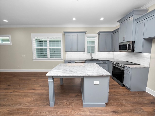 kitchen with sink, backsplash, appliances with stainless steel finishes, and a kitchen island