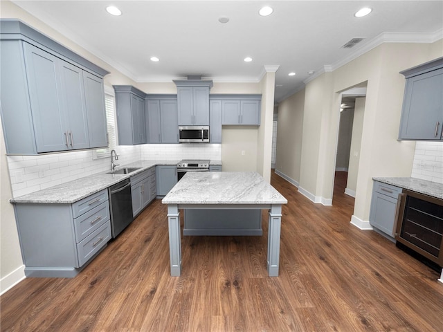 kitchen with dark hardwood / wood-style floors, appliances with stainless steel finishes, a center island, and sink