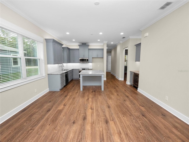 kitchen featuring tasteful backsplash, appliances with stainless steel finishes, gray cabinetry, and a center island