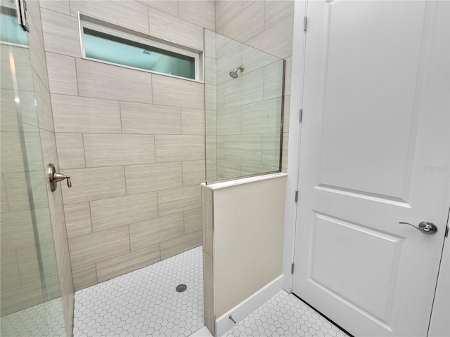 bathroom with tiled shower and tile patterned flooring