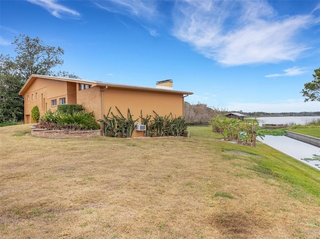 view of home's exterior with a lawn and a water view