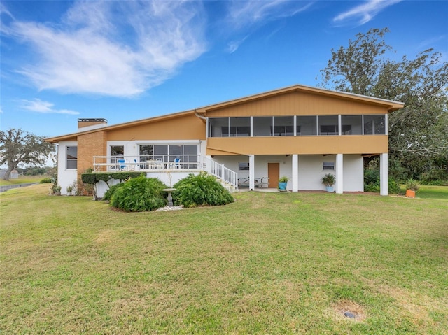 rear view of property with a lawn and a sunroom