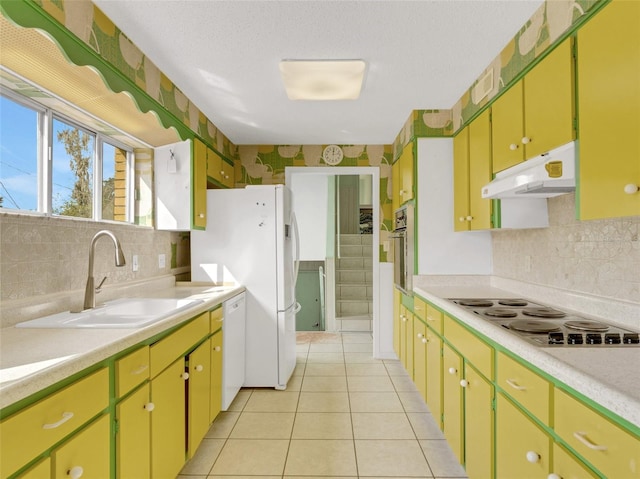 kitchen featuring white appliances, a textured ceiling, light tile patterned floors, backsplash, and sink