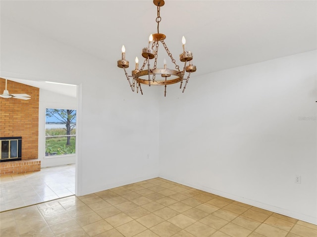 tiled empty room with lofted ceiling, a brick fireplace, and ceiling fan with notable chandelier