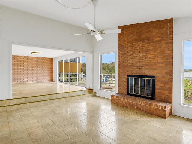 unfurnished living room featuring vaulted ceiling, brick wall, light tile patterned floors, a fireplace, and ceiling fan