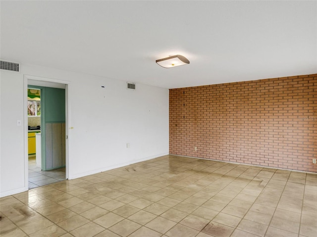 tiled spare room featuring brick wall