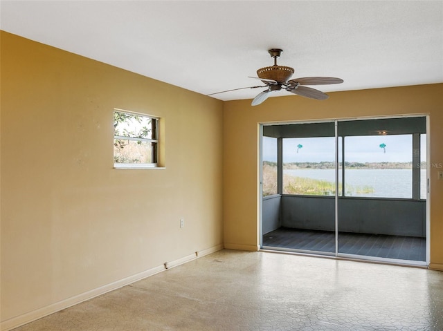 empty room with plenty of natural light, ceiling fan, and a water view