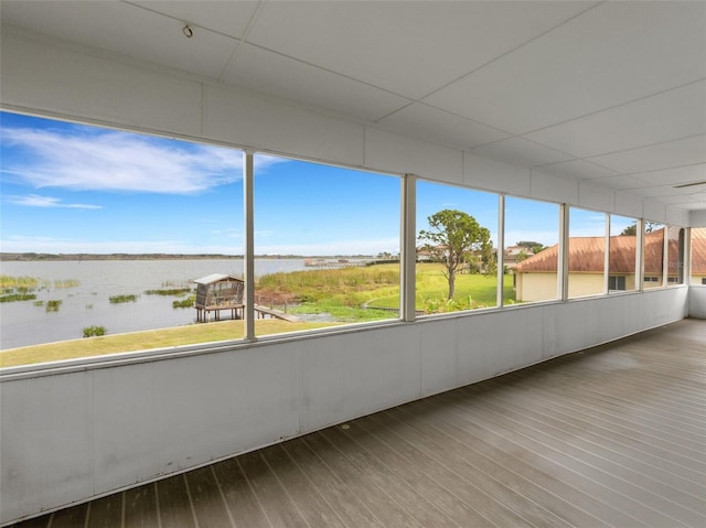 unfurnished sunroom featuring a drop ceiling and a water view