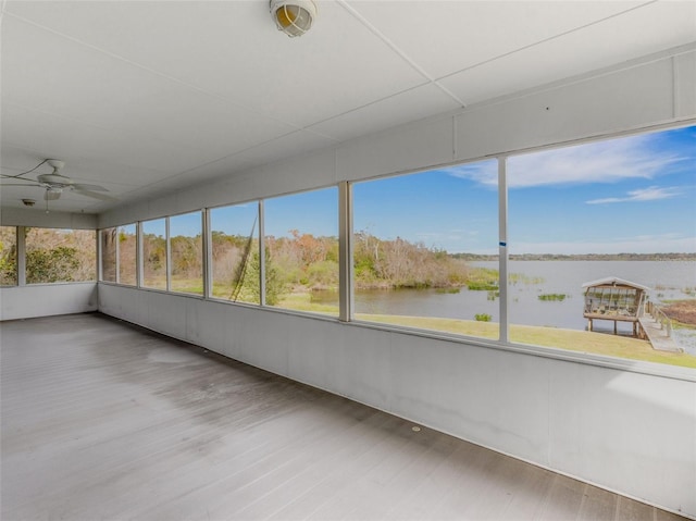 unfurnished sunroom with ceiling fan and a water view