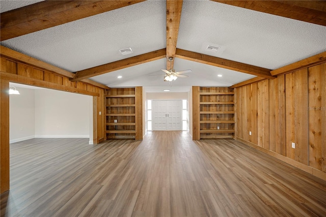 unfurnished living room with built in shelves, hardwood / wood-style floors, and a textured ceiling