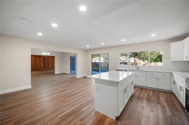 kitchen with white cabinets, a textured ceiling, tasteful backsplash, and a kitchen island