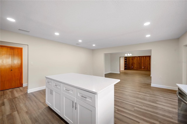 kitchen featuring dishwasher, a center island, a textured ceiling, white cabinets, and light wood-type flooring