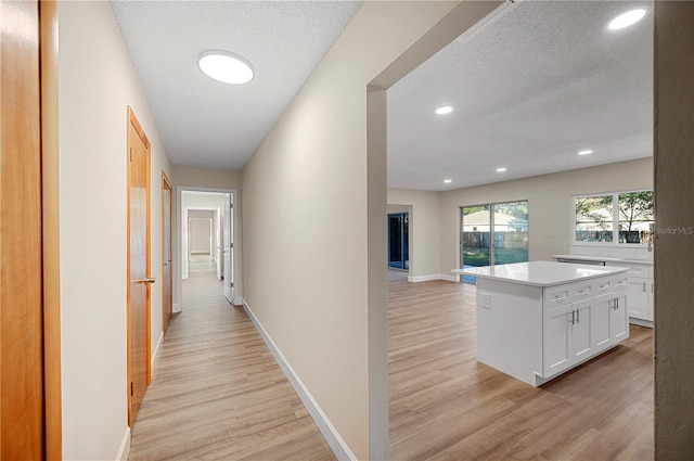 hall with light hardwood / wood-style floors and a textured ceiling