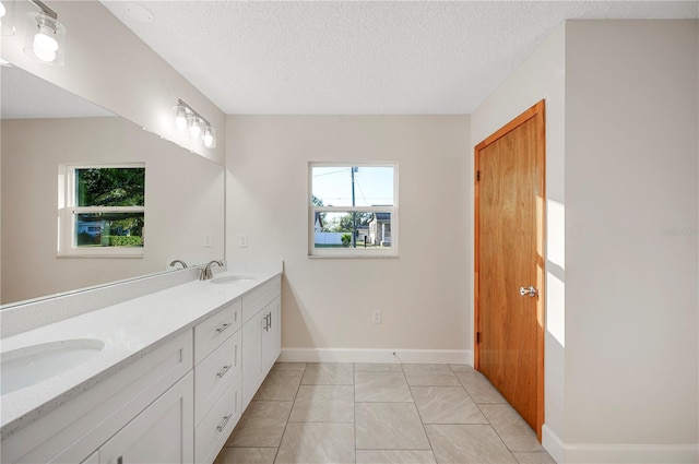 bathroom with tile patterned floors, vanity, and a textured ceiling