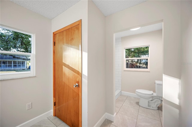 bathroom featuring tile patterned flooring, a textured ceiling, toilet, and walk in shower