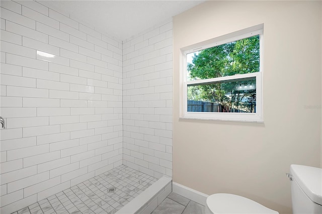 bathroom featuring a tile shower and toilet