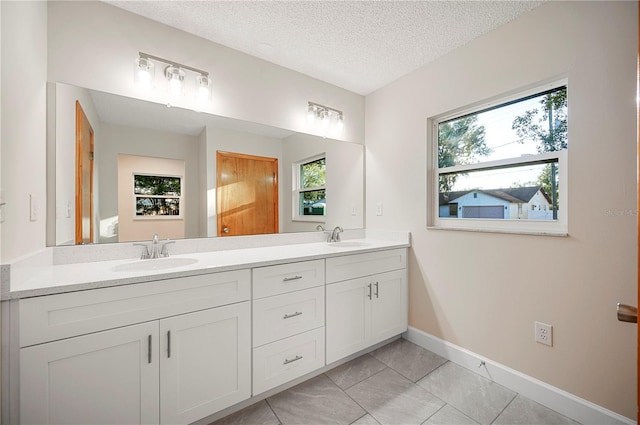 bathroom with plenty of natural light, vanity, a textured ceiling, and tile patterned flooring