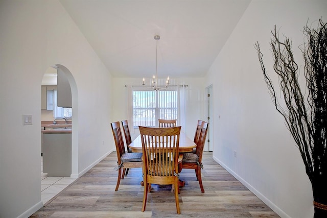 dining space with high vaulted ceiling, an inviting chandelier, and light wood-type flooring