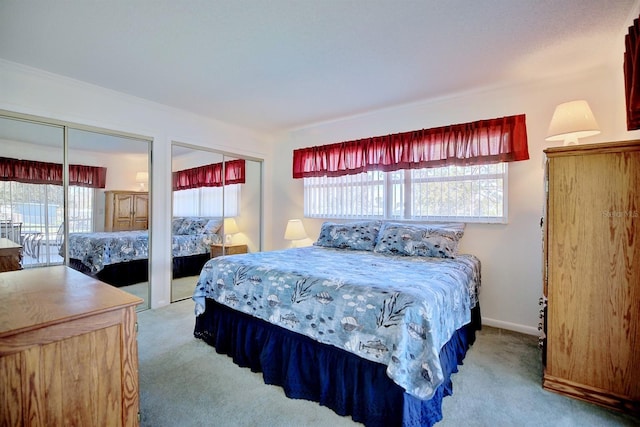 carpeted bedroom with multiple windows and two closets