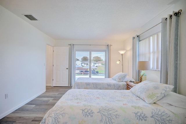 bedroom featuring wood-type flooring, a textured ceiling, and access to outside