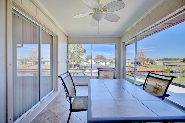 sunroom / solarium with plenty of natural light, ceiling fan, and a water view