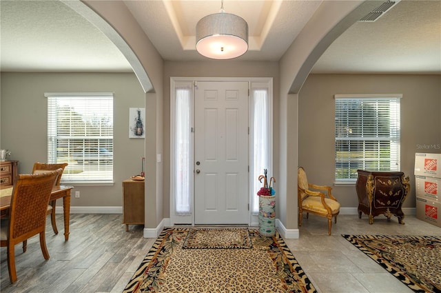 entrance foyer featuring a raised ceiling and light hardwood / wood-style flooring