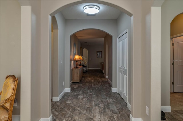 hallway with dark hardwood / wood-style floors and a textured ceiling