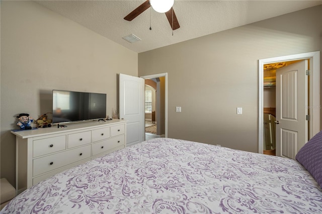 bedroom with lofted ceiling, ceiling fan, a textured ceiling, a walk in closet, and a closet