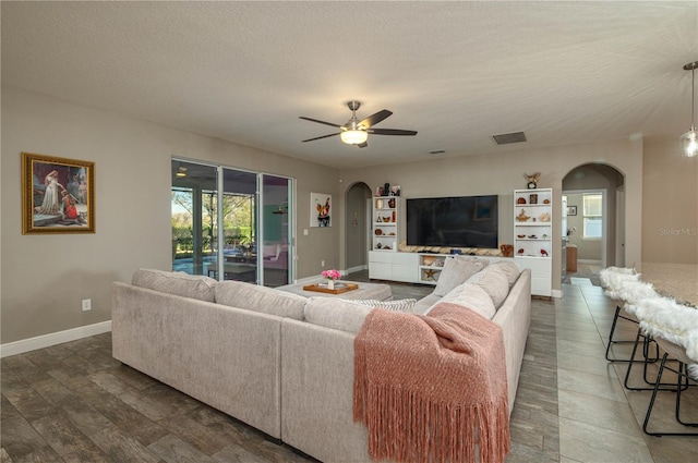 living room with ceiling fan and a textured ceiling