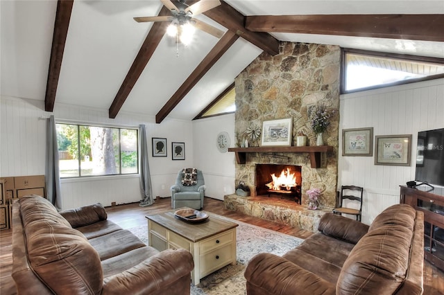 living room featuring high vaulted ceiling, light hardwood / wood-style flooring, beam ceiling, and a stone fireplace