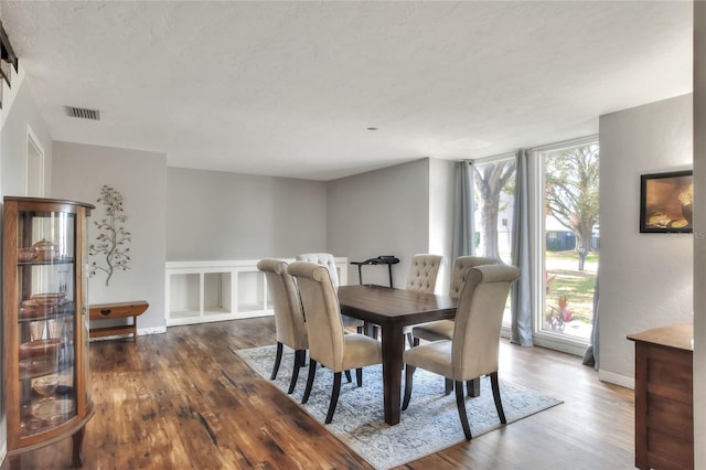 dining area featuring a wall of windows and dark hardwood / wood-style flooring