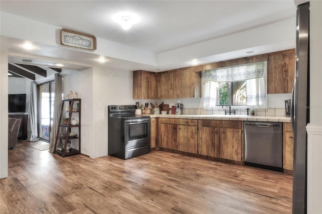 kitchen featuring sink, stainless steel appliances, hardwood / wood-style floors, and tile counters