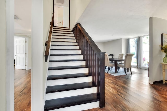 stairway with floor to ceiling windows and hardwood / wood-style floors