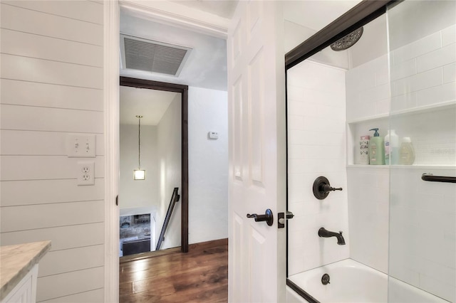 bathroom featuring tiled shower / bath combo, wood walls, wood-type flooring, and vanity